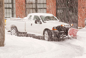 Truck with a Snowplow Clearing a Road During a Blizzard